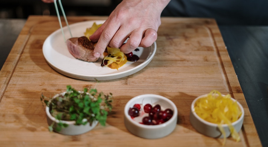 person-slicing-meat-on-brown-wooden-chopping-board-4253314